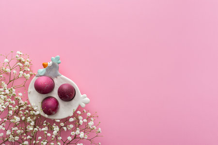 Spring Easter background, multi-colored Easter eggs in a decorative hen with gypsophila flowers on a pink background, copy spaceの写真素材
