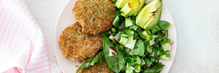 Quinoa cutlets and mixed salad with avocado and radishes, kiwi and water with lemon, delicious hearty breakfasts, vegan lunch plate bannerの写真素材