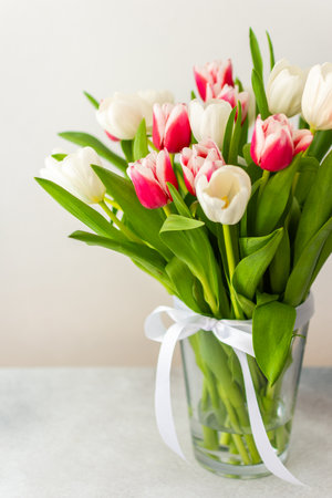 Beautiful spring bouquet of pink and white tulips in a glass vase, birthday or March 8th or mother's day conceptの写真素材