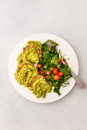 Enjoy a healthy breakfast with zucchini pancakes topped with green pea pesto, served with a mixed salad of fresh seasonal vegetables and herbs for a nutritious startの写真素材