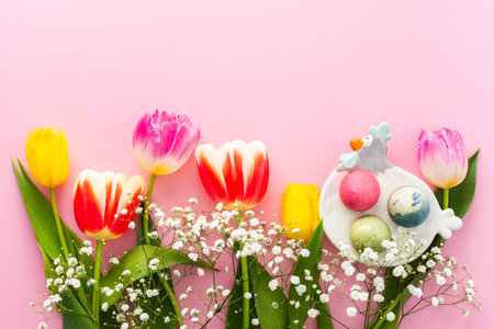 Spring Easter background, multi-colored Easter eggs and tulips with gypsophila on a pink background, copy spaceの写真素材
