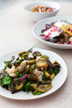 Pasta with baked vegetables and baked white fish and sardines, mixed salad with boiled beet and young cabbage and radishes with herbs, a delicious hearty lunch or dinnerの写真素材