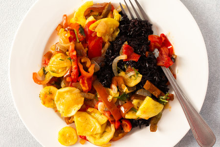 This wholesome breakfast includes black rice with stewed vegetables, with stewed tomatoes, zucchini, peppers and onionsの写真素材