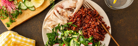 Delicious healthy breakfasts, chicken breast with red rice and salad mix with fresh seasonal organic vegetables and microgreens, top view of a plate with food and a cutting board with vegetablesの写真素材