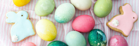 Multi-colored Easter eggs with decorative bunnies on a pink tablecloth, top view, Happy Easter holiday bannerの写真素材