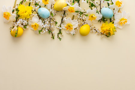 Festive background with spring flowers and Easter eggs on a yellow pastel backgroundの写真素材