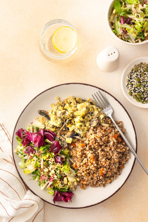 Delicious healthy breakfasts, buckwheat porridge with mixed salad with seeds and fried mushrooms with eggs, top view of plates with foodの写真素材