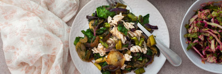 Pasta with baked vegetables and baked white fish and sardines, mixed salad with boiled beet and young cabbage and radishes with herbs, a delicious hearty lunch or dinner, bannerの写真素材