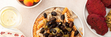 Savor gluten-free pasta with baked beans and zucchini, alongside beet pancakes with sunflower seed hummus. This vegetarian feast is a delicious and nutritious choice, bannerの写真素材