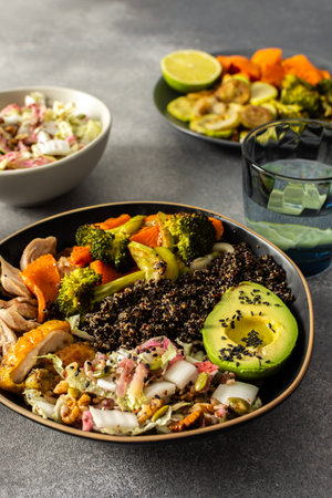 A hearty, balanced breakfast bowl with black quinoa, creamy avocado, roast chicken, sweet potatoes, zucchini, broccoli, and a fresh salad of cabbage and radish with chia and sesame seedsの写真素材