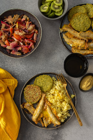 A savory, balanced breakfast with turmeric rice, baked ocean fish, broccoli pancakes, and roasted vegetable salad, providing essential proteins and healthy fats for an energizing startの写真素材
