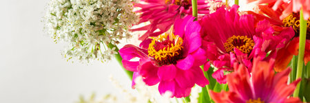 Summer bouquet of colorful Zinnia, onion inflorescences and mint sprigs, bouquet of flowers on the table near the wall, home decoration with flowers bannerの写真素材