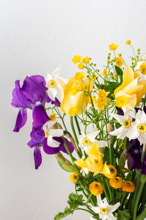 Home interior with a bouquet of spring flowers, Irises and yellow ranunculus, yellow tulips with white daffodilsの写真素材