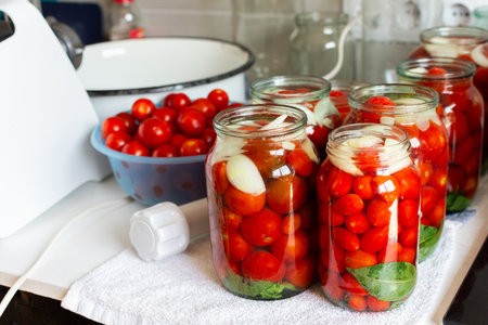 Homemade tomato preserves and tomato juice, canned and sealed for winter storage, maintaining flavor and freshness, kitchen table with prepared jars of tomatoesの写真素材