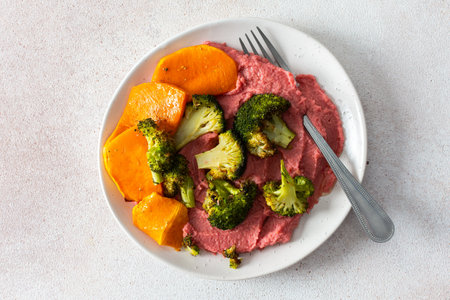 A healthy, balanced breakfast with beetroot hummus, roasted sweet potatoes, and broccoli, topped with a fresh pink radish and Chinese cabbage salad with chia seedsの写真素材