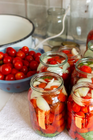 Preserving fresh tomatoes and tomato juice for the winter, stored in airtight jars for long-term use, kitchen table with prepared jars of tomatoesの写真素材