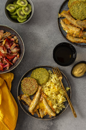 A savory, balanced breakfast with turmeric rice, baked ocean fish, broccoli pancakes, and roasted vegetable salad, providing essential proteins and healthy fats for an energizing startの写真素材