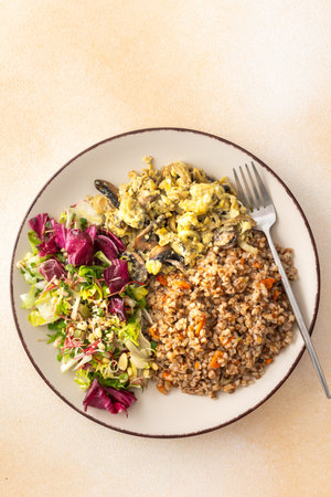 Delicious healthy breakfasts, buckwheat porridge with mixed salad with seeds and fried mushrooms with eggs, top view of plates with foodの写真素材