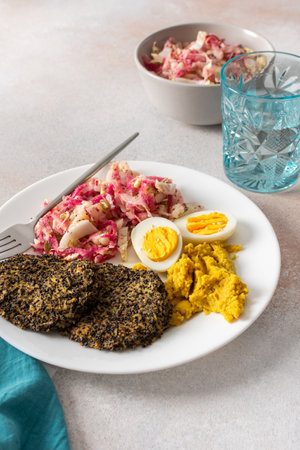 A nutritious breakfast featuring quinoa pancakes, fresh cabbage, radish, mung bean sprouts, boiled eggs, hummus, and roasted beets, perfect for a balanced start to your dayの写真素材