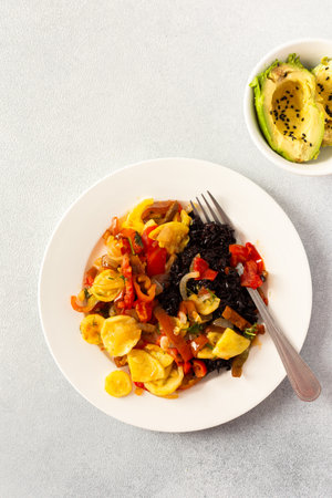 This wholesome breakfast includes black rice with stewed vegetables, with stewed tomatoes, zucchini, peppers and onionsの写真素材