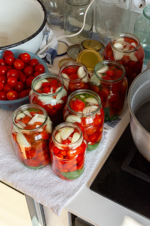 Preserving fresh tomatoes and tomato juice for the winter, stored in airtight jars for long-term use, kitchen table with prepared jars of tomatoesの写真素材