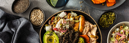 A vibrant, protein-packed breakfast with black quinoa, avocado, chicken, roasted veggies like sweet potato, broccoli, and a fresh salad of cabbage, radish, chia, and sesame seeds, bannerの写真素材
