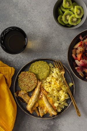 A savory, balanced breakfast with turmeric rice, baked fish, broccoli pancakes, and roasted vegetable salad, providing essential proteins and healthy fats for an energizing startの写真素材