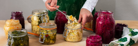 Fermenting different cabbages, white and red cabbage, Brussels and cauliflower, broccoli, woman fermenting sauerkraut, bannerの写真素材