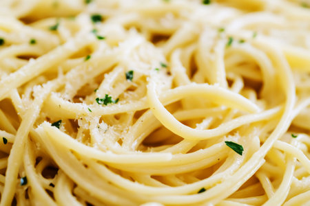 A plate of freshly cooked traditional Italian pasta is served with a light coating of garlic and olive oil. The dish is garnished with fresh herbs and grated cheese for added flavorの素材