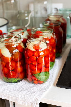 Preserving fresh tomatoes and tomato juice for the winter, stored in airtight jars for long-term use, kitchen table with prepared jars of tomatoesの写真素材