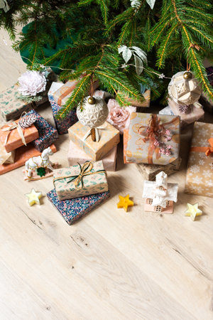 A cozy Christmas scene with elegant natural-toned gift boxes placed under a Christmas tree, lit with festive lights evoking peace and seasonal joyの写真素材