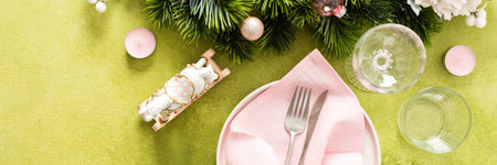 Top view of an elegant Christmas table with an empty plate, folded pink napkin and cutlery on a...