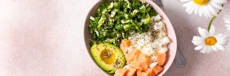 A nutritious breakfast bowl featuring rice, salmon, avocado, and fresh greens is presented...