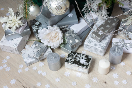 Steel-colored gift boxes paired with glowing candles and delicate decorations under a lush tree, creating an elegant festive holiday atmosphereの写真素材