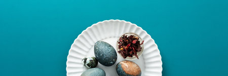A decorative plate displays several uniquely colored Easter eggs, showcasing shades of blue and...