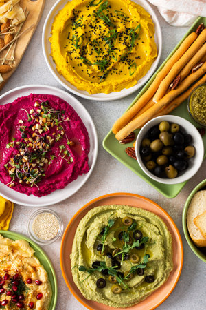 Colorful spread features beetroot, classic, broccoli, and turmeric hummus showcased on a charcuterie...