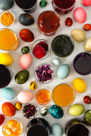Colorful Easter eggs surround various bowls filled with natural dyes such as beets, turmeric and flower extracts hibiscus, red cabbage and onion peel, showcasing a creative egg decorating processの写真素材