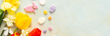 Bright tulips and daffodils surround playful Easter cookies and candies, showcasing the vibrant...