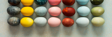 A beautiful array of hand-dyed Easter eggs in various colors, neatly arranged in rows. This colorful...