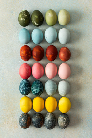 A beautiful array of hand-dyed Easter eggs in various colors, neatly arranged in rows. This colorful...