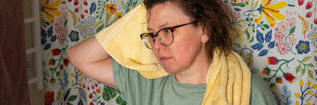 A 50-year-old woman starts her morning routine in the bathroom. She looks at herself in the mirror...