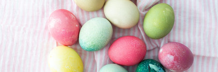 Multi-colored Easter eggs on a pink tablecloth, top view, Happy Easter holiday banner