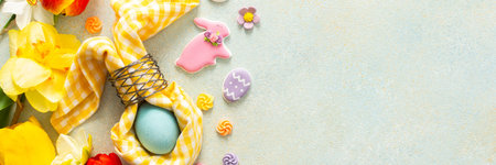 Bright spring flowers surround a beautifully set table with pastel Easter eggs, candy, and...