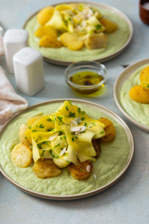 Baked potatoes are topped with slices of fermented zucchini and served alongside a green pea sauce with broccoli. This meal is prepared for a healthy breakfastの写真素材
