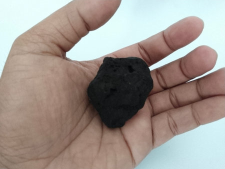 Close-up of a dark coal held in a person's palm against