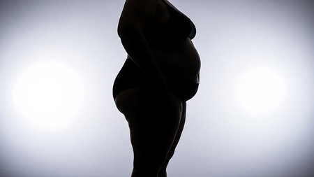 Side profile silhouette of a plussize womans body in underwear against a bright abstract backgroundの素材