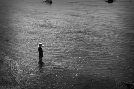 Little kid in the water with a hatの写真素材