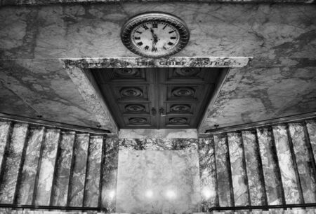 Looking down at stairs and a door and clock in Black and whiteの写真素材
