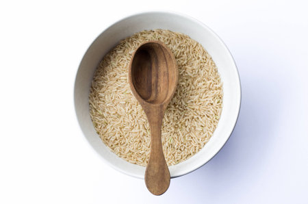 brown rice  in white bowl and wooden spoonの写真素材