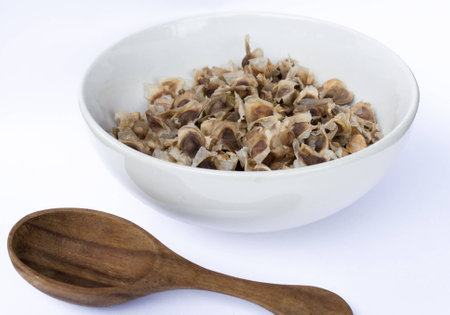 Moringa seeds dry in white bowl and wooden spoonの写真素材